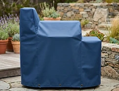 Navy vinyl cover fitted over an offset smoker on a stone patio