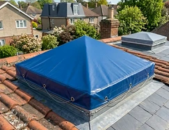 Blue vinyl cover fitted over a pyramid skylight on a tile roof
